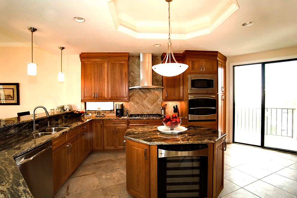 Photo of a large contemporary u-shaped eat-in kitchen in Tampa with a double-bowl sink, raised-panel cabinets, medium wood cabinets, granite benchtops, beige splashback, stone tile splashback, stainless steel appliances, porcelain floors and with island.