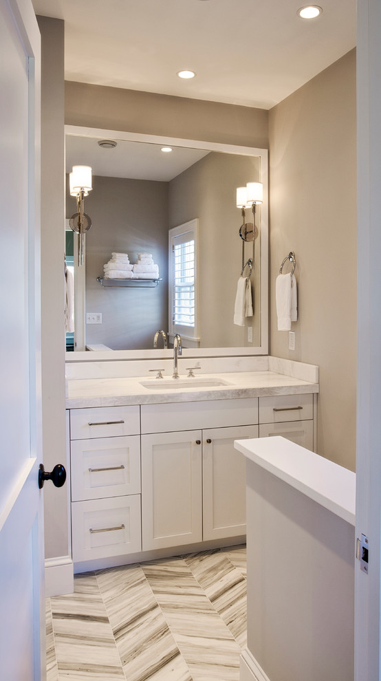 Design ideas for a mid-sized transitional powder room in Boston with recessed-panel cabinets, white cabinets, beige walls, porcelain floors, an undermount sink, marble benchtops and multi-coloured floor.