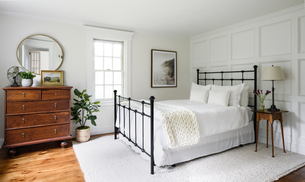 Country guest bedroom in Boston with medium hardwood floors and panelled walls.