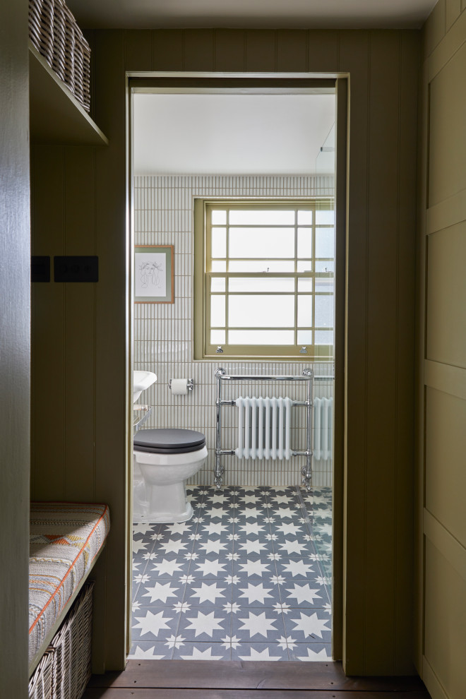 Foto på ett litet vintage toalett, med öppna hyllor, en toalettstol med separat cisternkåpa, vit kakel, stickkakel, beige väggar, cementgolv, ett piedestal handfat och svart golv