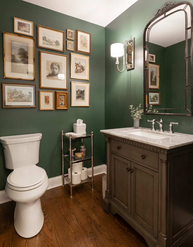 Photo of a mid-sized eclectic powder room in Chicago with furniture-like cabinets, brown cabinets, green walls, medium hardwood floors, an undermount sink, engineered quartz benchtops, brown floor, beige benchtops and a freestanding vanity.