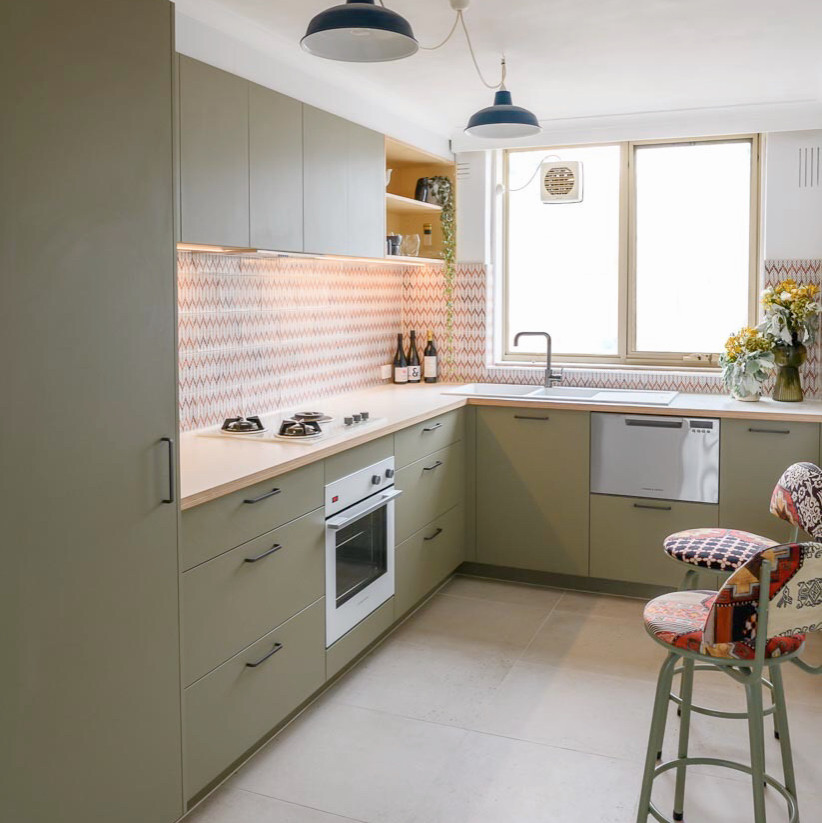 Inspiration for a small scandinavian l-shaped separate kitchen in Melbourne with a double-bowl sink, flat-panel cabinets, green cabinets, laminate benchtops, ceramic splashback, white appliances, ceramic floors, beige floor, orange splashback and beige benchtop.
