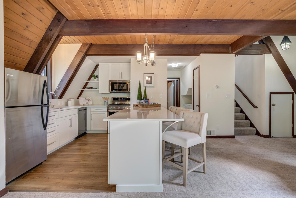 Inspiration for a country l-shaped kitchen in Sacramento with an undermount sink, shaker cabinets, white cabinets, stainless steel appliances, medium hardwood floors, with island, brown floor and white benchtop.