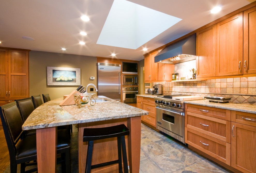 Large arts and crafts u-shaped open plan kitchen in Seattle with an undermount sink, shaker cabinets, light wood cabinets, granite benchtops, green splashback, stone tile splashback, stainless steel appliances, slate floors and with island.