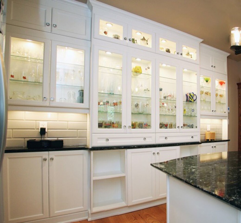 Example of a large transitional medium tone wood floor kitchen design with recessed-panel cabinets, white cabinets, granite countertops, white backsplash, glass tile backsplash and an island