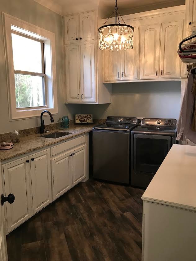 This is an example of a mid-sized traditional u-shaped dedicated laundry room in New Orleans with an undermount sink, raised-panel cabinets, white cabinets, granite benchtops, porcelain floors and a side-by-side washer and dryer.