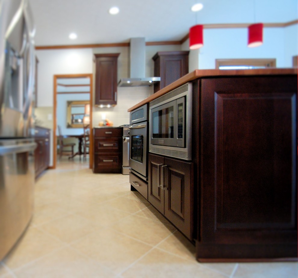 Inspiration for a large transitional l-shaped eat-in kitchen remodel in Columbus with an undermount sink, raised-panel cabinets, dark wood cabinets, granite countertops, gray backsplash, ceramic backsplash, stainless steel appliances and an island