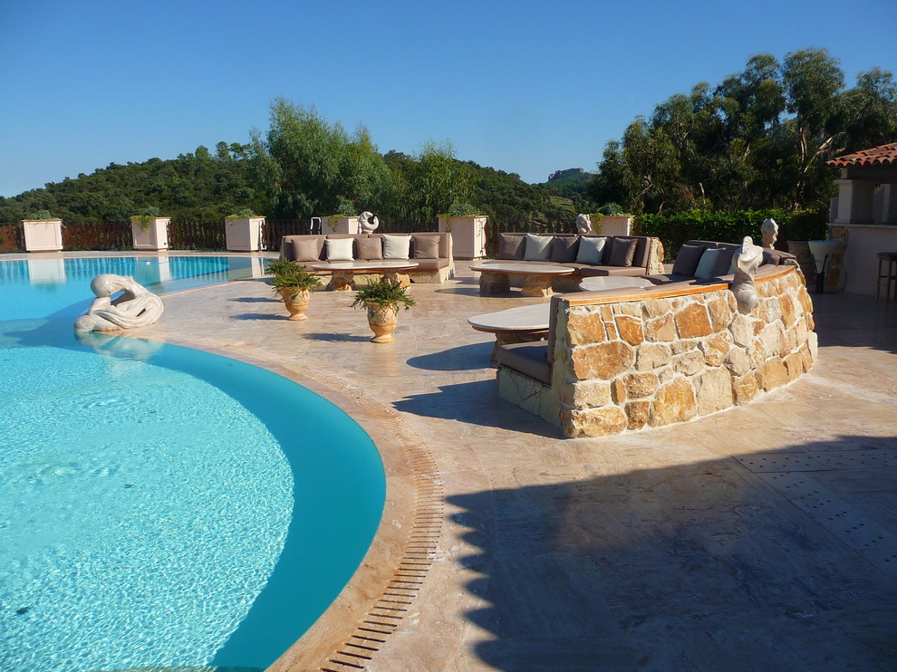 Large backyard custom-shaped pool in Nice with natural stone pavers.