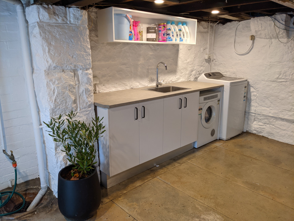 Diseño de cuarto de lavado de galera rústico de tamaño medio con fregadero encastrado, puertas de armario blancas, suelo de cemento y ladrillo