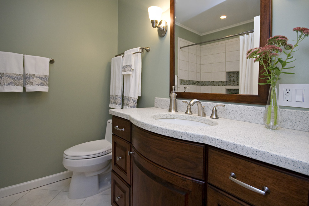 Inspiration for a small transitional kids bathroom in Raleigh with raised-panel cabinets, dark wood cabinets, an alcove tub, a shower/bathtub combo, a one-piece toilet, beige tile, cement tile, green walls, ceramic floors, an undermount sink, concrete benchtops, beige floor, a shower curtain and white benchtops.