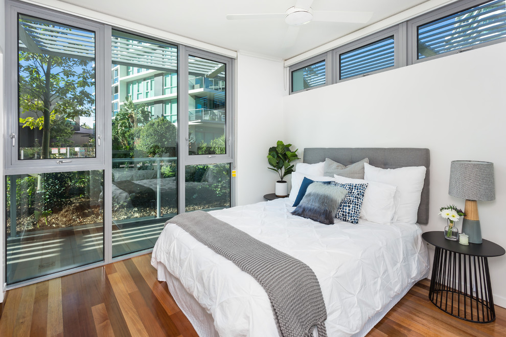 Inspiration for a beach style bedroom in Brisbane with white walls, medium hardwood floors and brown floor.