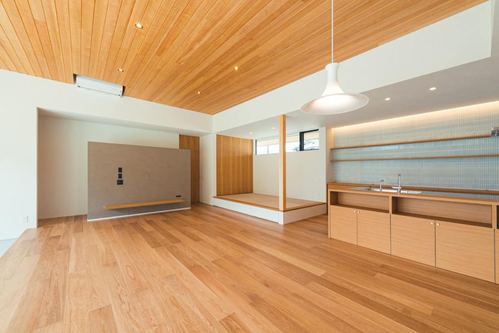 Aménagement d'un salon ouvert avec un mur blanc, un sol en bois brun, un téléviseur fixé au mur, un sol marron, un plafond en bois et du papier peint.