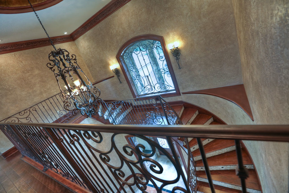 Large tuscan wooden curved staircase photo in Houston with glass risers
