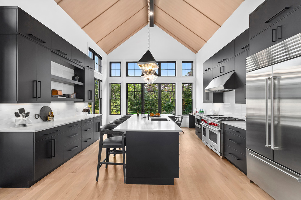 Inspiration for a large contemporary galley eat-in kitchen in New York with an undermount sink, flat-panel cabinets, black cabinets, quartz benchtops, white splashback, ceramic splashback, stainless steel appliances, light hardwood floors, with island, beige floor and white benchtop.