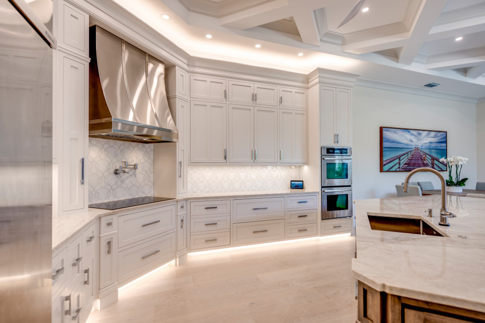 Inspiration for a transitional u-shaped light wood floor, beige floor and coffered ceiling open concept kitchen remodel with an undermount sink, beaded inset cabinets, white cabinets, quartzite countertops, white backsplash, stone tile backsplash, stainless steel appliances, an island and gray countertops