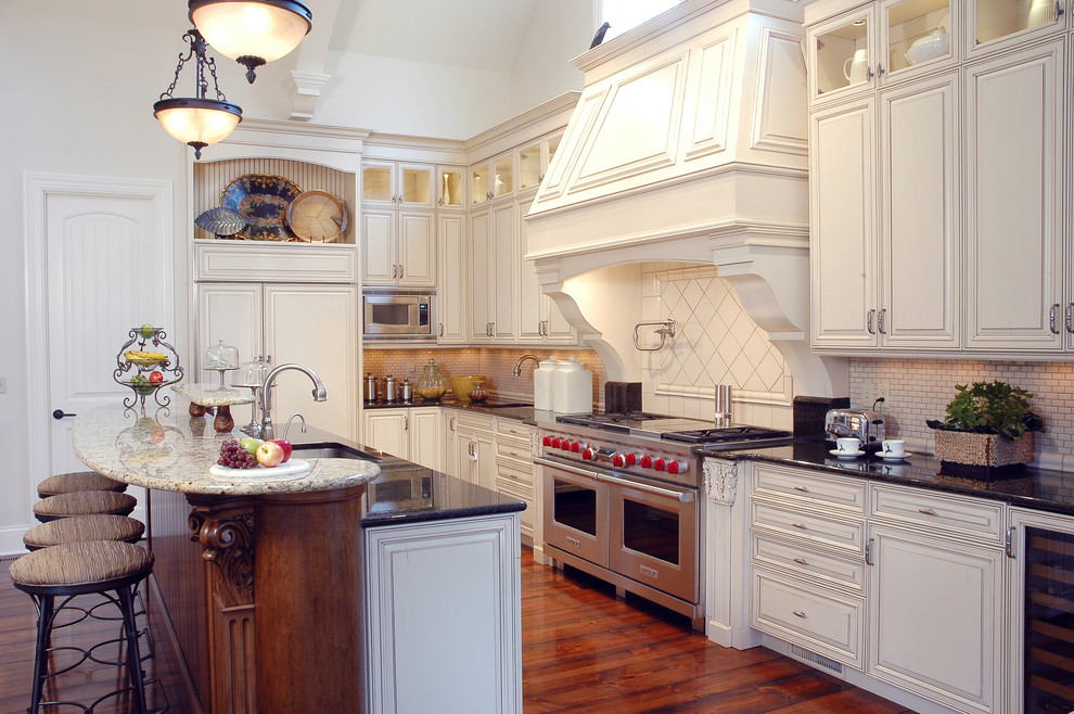 Photo of a traditional l-shaped kitchen in St Louis with an undermount sink, raised-panel cabinets, beige cabinets, beige splashback, mosaic tile splashback, stainless steel appliances and dark hardwood floors.