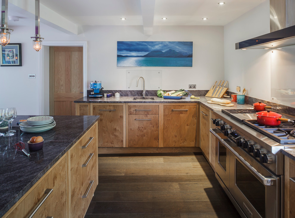 Inspiration for a contemporary l-shaped kitchen in Wiltshire with granite benchtops, an undermount sink, flat-panel cabinets, medium wood cabinets, glass sheet splashback, stainless steel appliances, medium hardwood floors and with island.