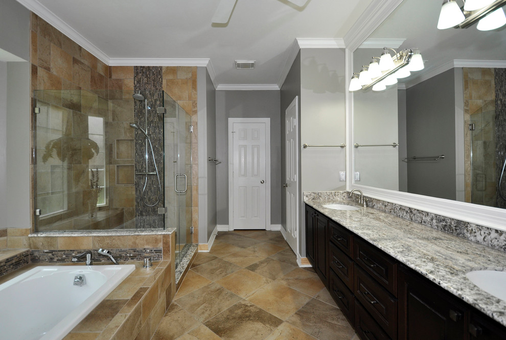 This is an example of a medium sized traditional ensuite bathroom in Houston with a submerged sink, raised-panel cabinets, dark wood cabinets, a one-piece toilet, beige tiles, grey walls, a built-in bath and a corner shower.