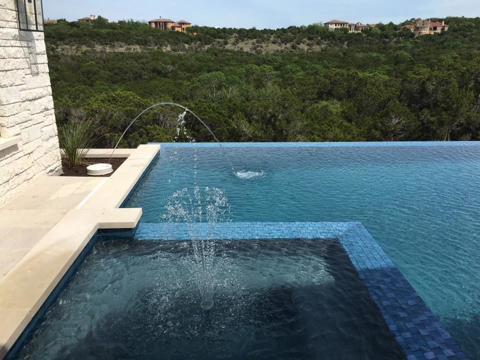 Inspiration for a large modern backyard concrete and rectangular infinity hot tub remodel in Austin