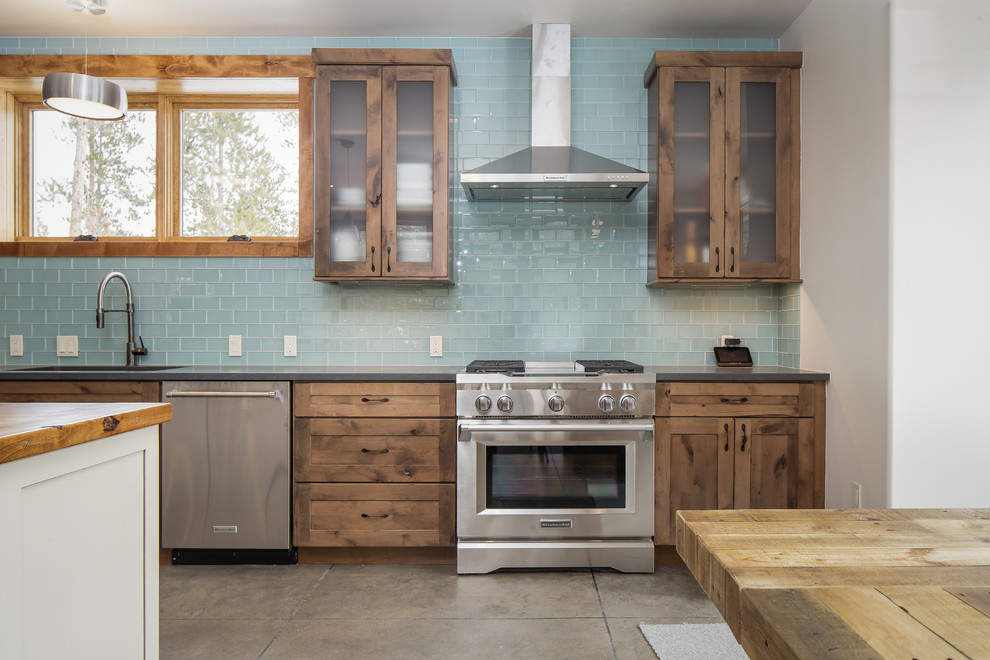 Inspiration for a mid-sized rustic single-wall eat-in kitchen remodel in Denver with an undermount sink, shaker cabinets, distressed cabinets, quartz countertops, blue backsplash, glass tile backsplash, stainless steel appliances, an island and gray countertops