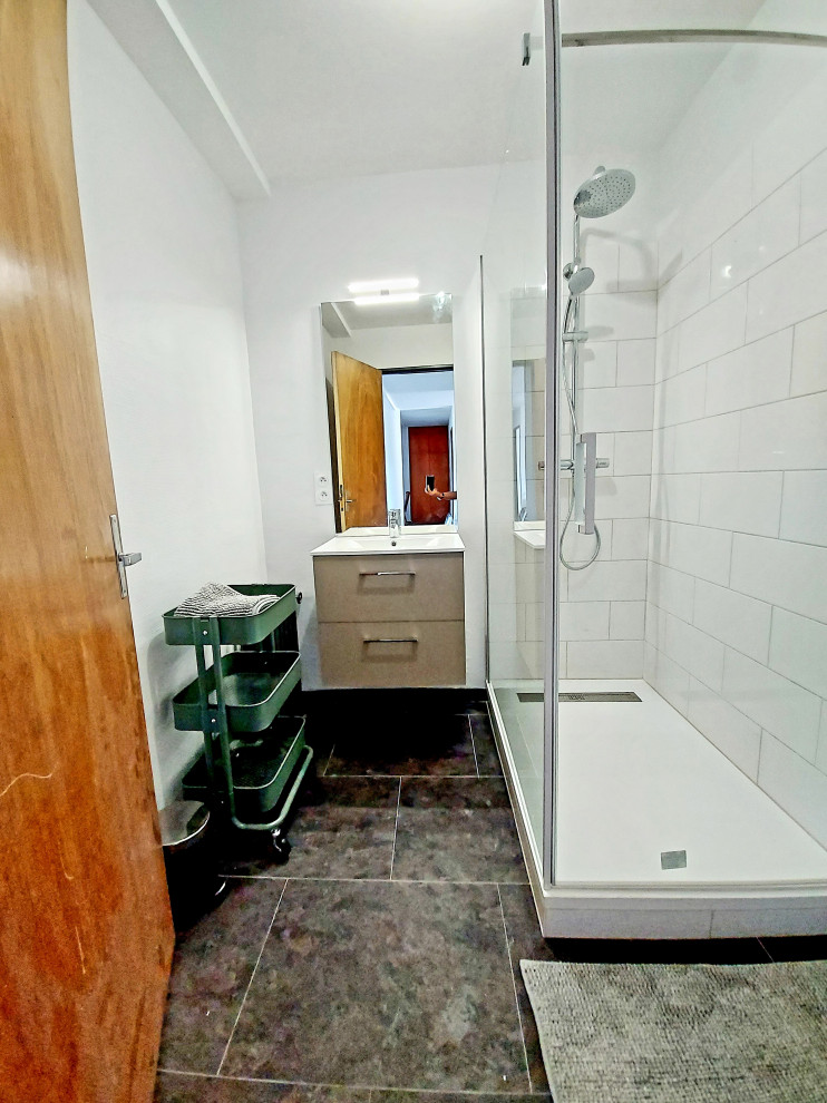 Photo of a small contemporary 3/4 bathroom in Paris with a curbless shower, white tile, ceramic tile, white walls, vinyl floors, a console sink, black floor, a hinged shower door, white benchtops and a single vanity.
