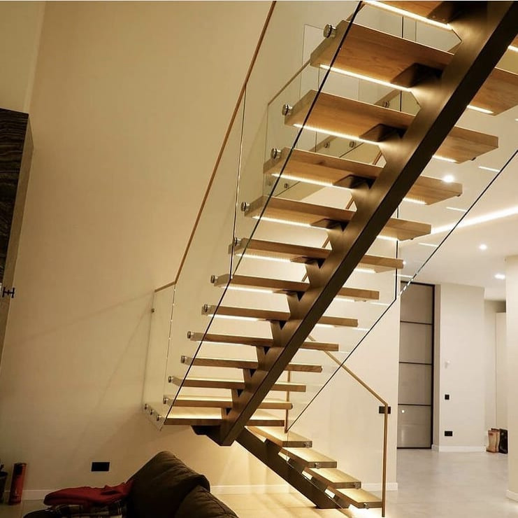 На фото: изогнутая деревянная лестница среднего размера в классическом стиле с деревянными ступенями и стеклянными перилами