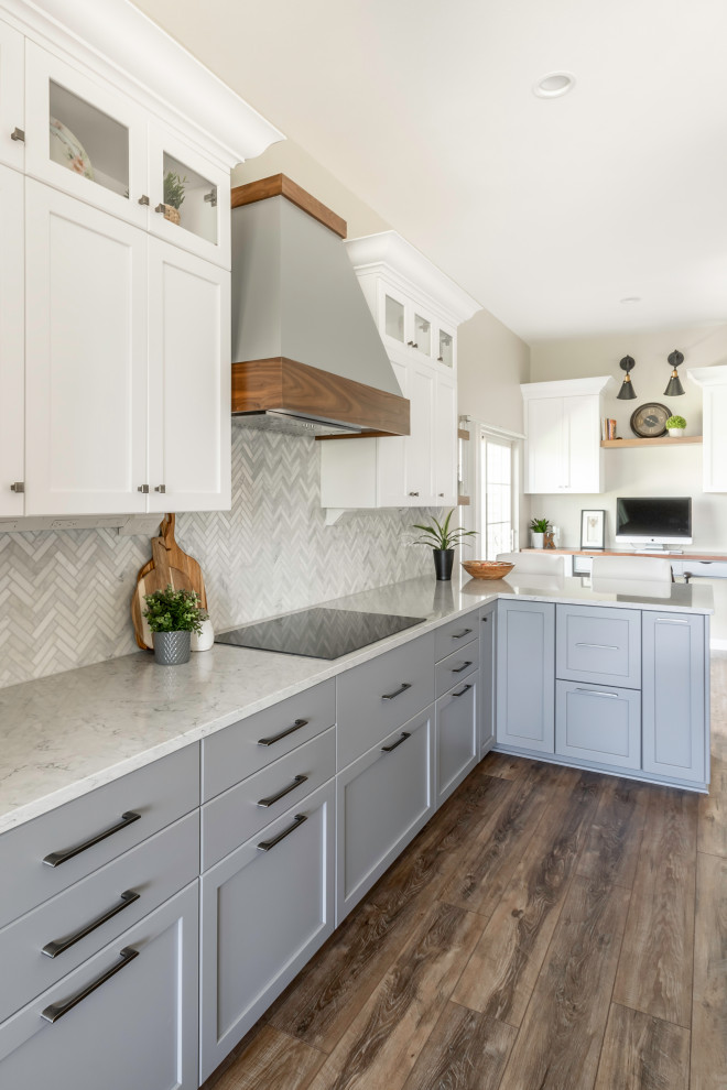 This is an example of a large contemporary l-shaped open plan kitchen in Milwaukee with a double-bowl sink, shaker cabinets, white cabinets, quartz benchtops, white splashback, marble splashback, stainless steel appliances, vinyl floors, with island, brown floor and white benchtop.