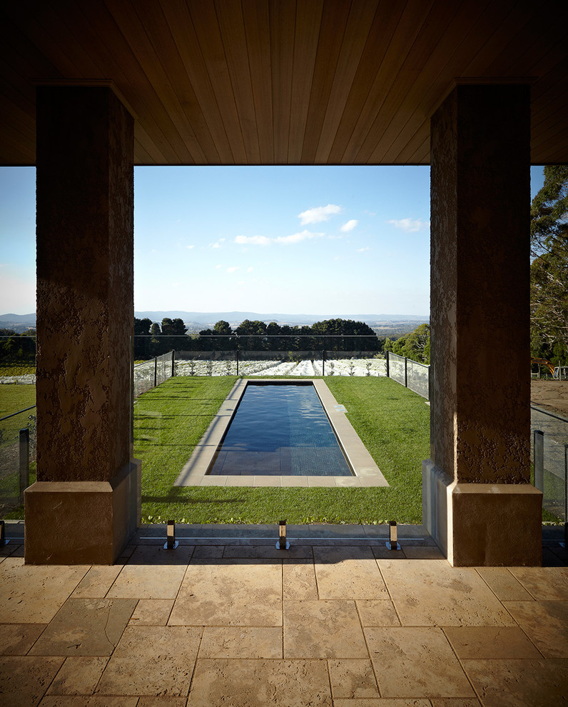 This is an example of an expansive country backyard custom-shaped lap pool in Melbourne with natural stone pavers.