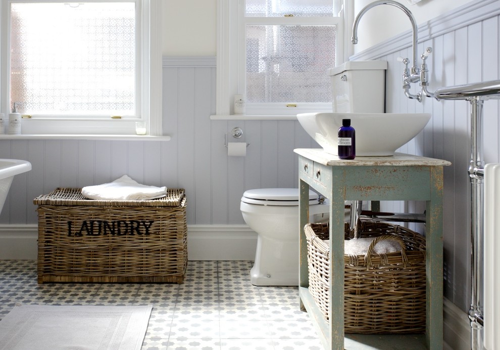 Mid-sized traditional kids bathroom in Sussex with a vessel sink, furniture-like cabinets, distressed cabinets, a claw-foot tub, a shower/bathtub combo, a two-piece toilet, multi-coloured tile, cement tile and beige walls.