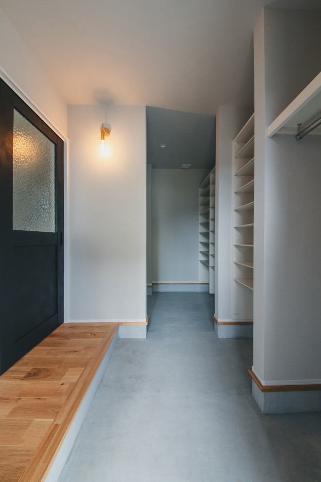 На фото: прихожая со шкафом для обуви в стиле лофт с белыми стенами, одностворчатой входной дверью, черной входной дверью, серым полом, потолком с обоями и обоями на стенах