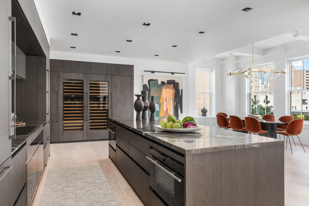 Mid-sized contemporary single-wall eat-in kitchen in New York with glass-front cabinets, dark wood cabinets, panelled appliances, light hardwood floors and with island.