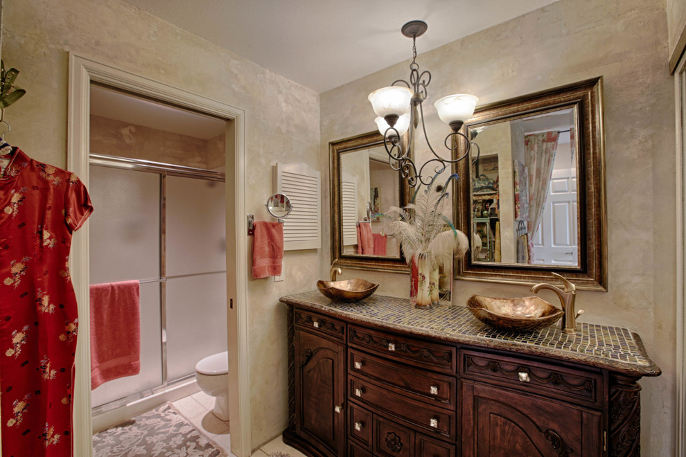Design ideas for a mid-sized traditional 3/4 bathroom in Denver with furniture-like cabinets, dark wood cabinets, an alcove shower, a two-piece toilet, beige walls, ceramic floors, a vessel sink, tile benchtops, white floor, a sliding shower screen and brown benchtops.