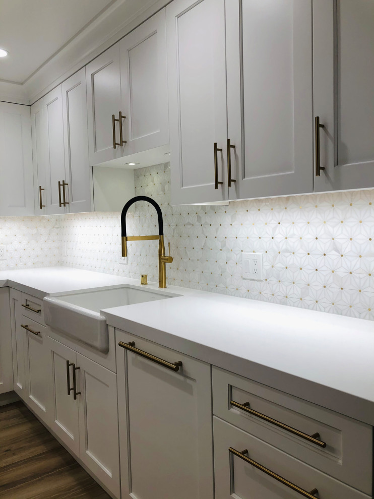 Eat-in kitchen - mid-sized transitional l-shaped medium tone wood floor and brown floor eat-in kitchen idea in San Francisco with a farmhouse sink, recessed-panel cabinets, white cabinets, quartz countertops, white backsplash, mosaic tile backsplash, stainless steel appliances, a peninsula and white countertops