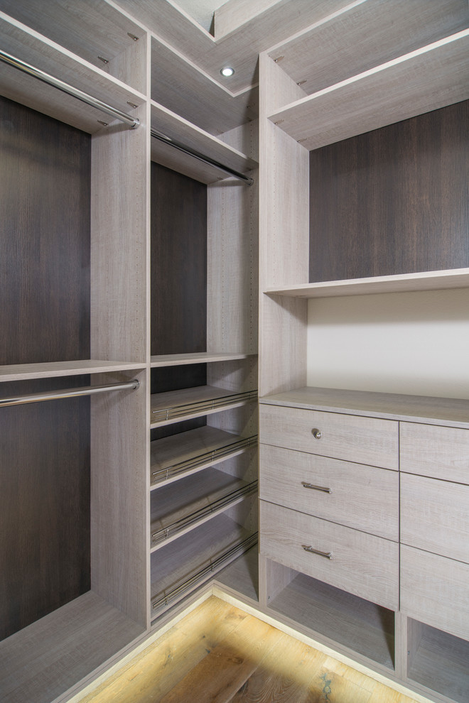 This is an example of a contemporary walk-in wardrobe in San Francisco with flat-panel cabinets and light wood cabinets.