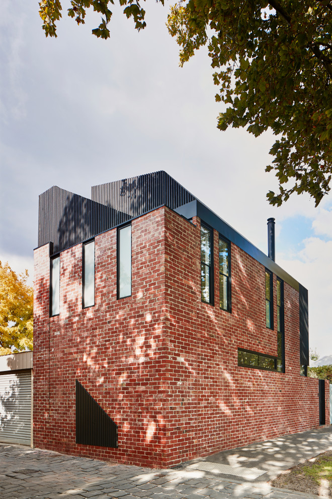 Foto della facciata di una casa a schiera grande nera industriale a due piani con rivestimento in mattoni, tetto nero e pannelli e listelle di legno
