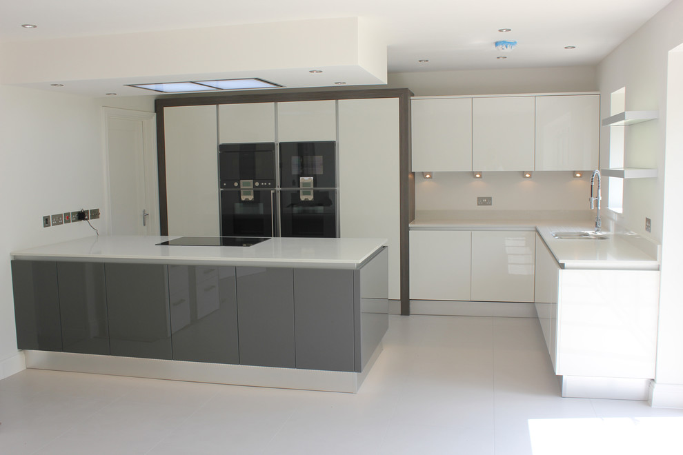 Photo of a large contemporary l-shaped eat-in kitchen in Dorset with an undermount sink, flat-panel cabinets, grey cabinets, quartz benchtops, black appliances, porcelain floors and with island.