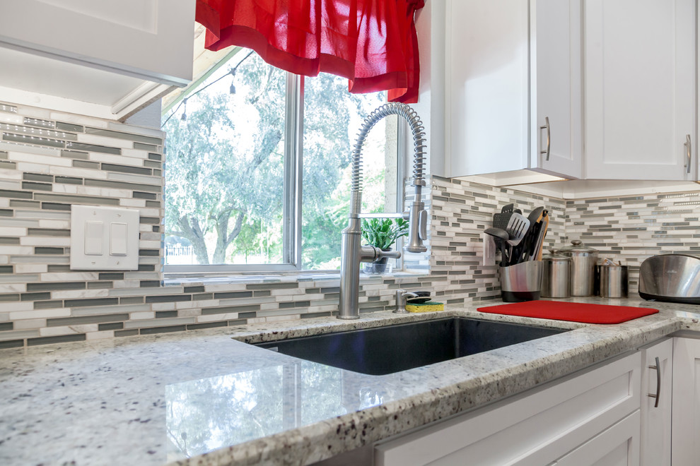 Open concept kitchen - mid-sized transitional u-shaped laminate floor and brown floor open concept kitchen idea in Phoenix with an undermount sink, recessed-panel cabinets, white cabinets, granite countertops, multicolored backsplash, mosaic tile backsplash and stainless steel appliances