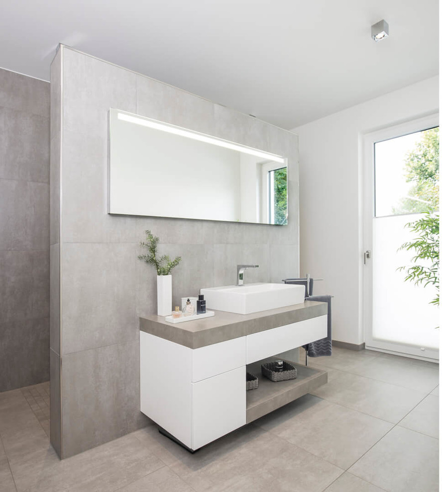 This is an example of a mid-sized contemporary bathroom with flat-panel cabinets, white cabinets, gray tile, a vessel sink, grey floor, stone slab, grey walls, concrete benchtops and grey benchtops.