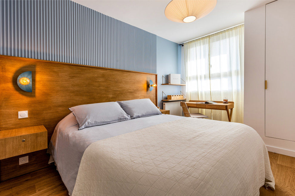 Modelo de dormitorio principal vintage de tamaño medio sin chimenea con paredes azules, suelo de madera clara, suelo marrón y boiserie