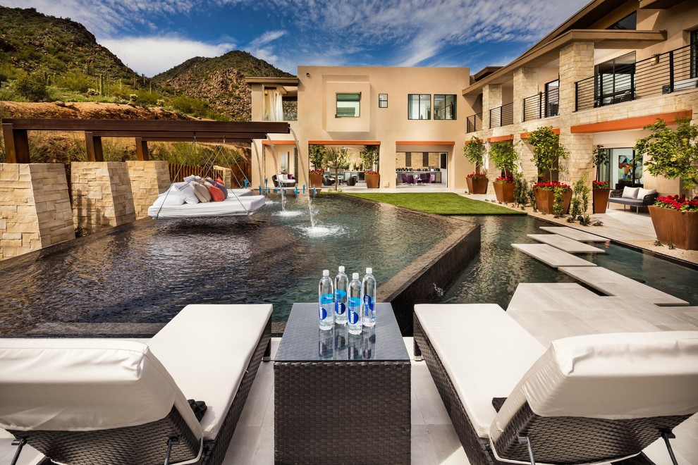 Expansive backyard custom-shaped infinity pool in Phoenix with a water feature and natural stone pavers.