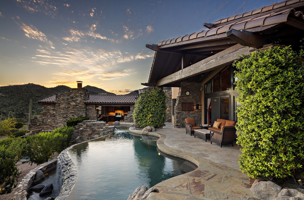 Inspiration for a country backyard custom-shaped infinity pool in Phoenix with a water feature and natural stone pavers.