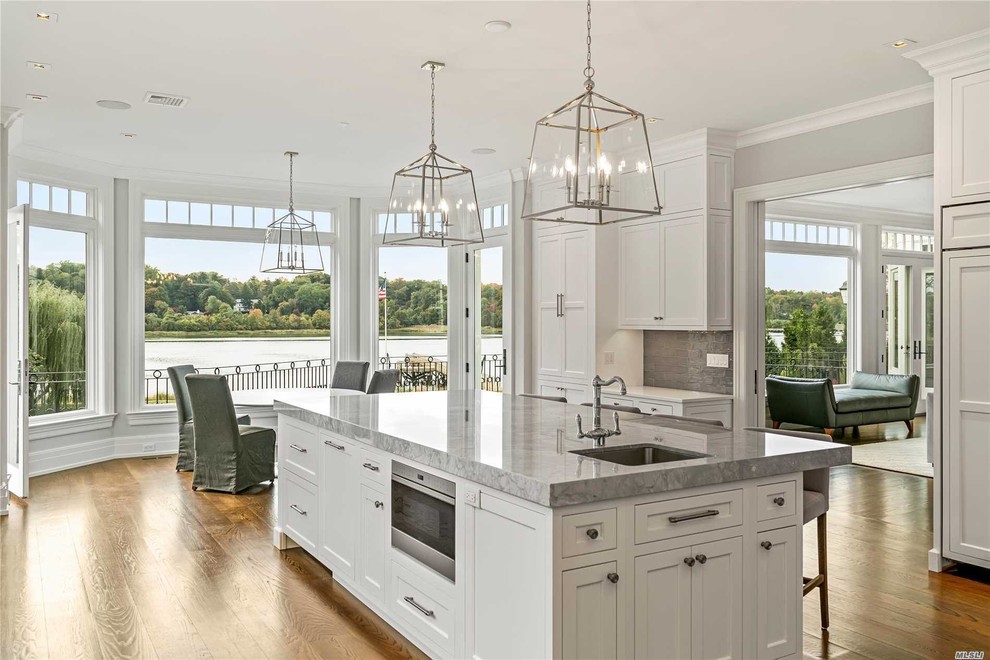Open concept kitchen - large transitional l-shaped dark wood floor and brown floor open concept kitchen idea with beaded inset cabinets, white cabinets, granite countertops, gray backsplash, glass tile backsplash, stainless steel appliances, an island and gray countertops