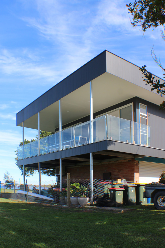 Design ideas for a small contemporary two-storey black house exterior in Central Coast with concrete fiberboard siding, a flat roof and a metal roof.