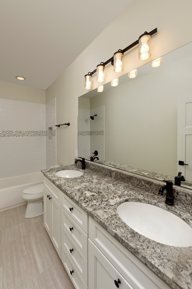 This is an example of a large arts and crafts bathroom in DC Metro with an undermount sink, shaker cabinets, white cabinets, granite benchtops, an alcove tub, a shower/bathtub combo, a two-piece toilet, beige tile, ceramic tile, beige walls, ceramic floors and beige floor.