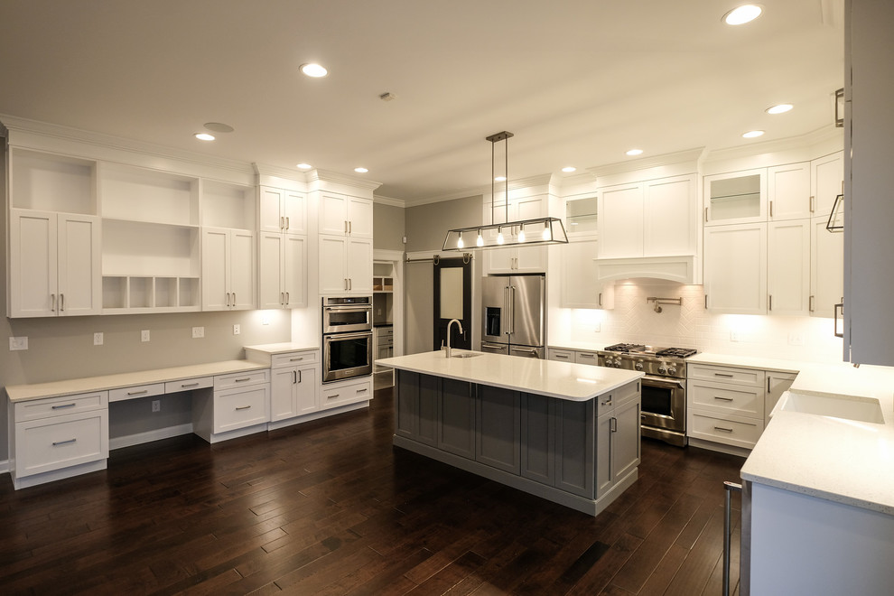 Eat-in kitchen - large transitional u-shaped dark wood floor and brown floor eat-in kitchen idea with a farmhouse sink, recessed-panel cabinets, white cabinets, quartz countertops, white backsplash, stainless steel appliances, an island and white countertops