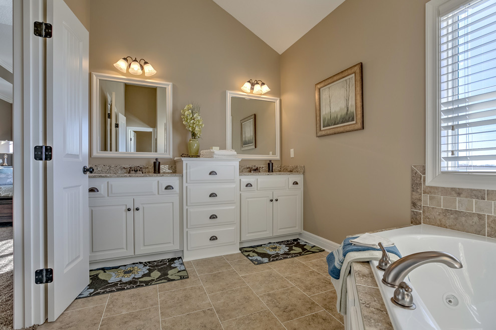 Mid-sized arts and crafts master bathroom in Kansas City with raised-panel cabinets, granite benchtops, beige tile, beige walls, ceramic floors, white cabinets, a corner tub, an alcove shower, beige floor and a hinged shower door.