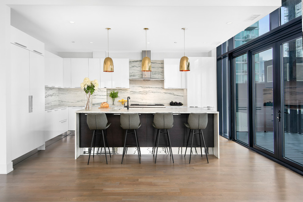 Contemporary l-shaped kitchen in Chicago with white cabinets, white splashback, with island, brown floor, grey benchtop, flat-panel cabinets, stone slab splashback, panelled appliances and medium hardwood floors.