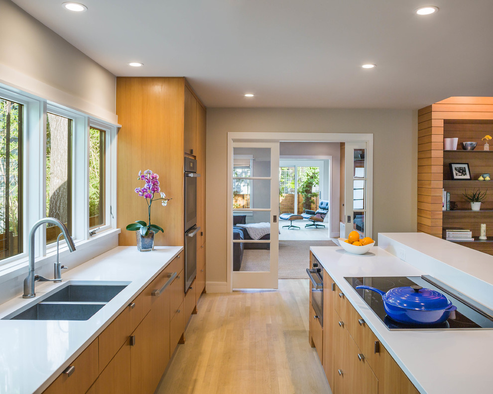 Contemporary kitchen with a double-bowl sink, flat-panel cabinets, medium wood cabinets and with island.