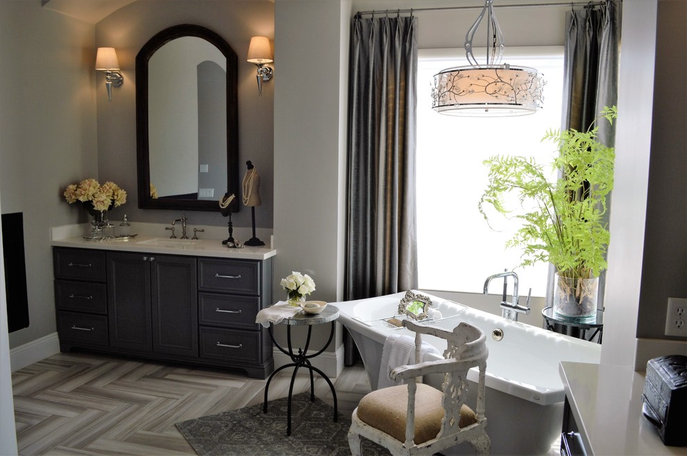 Freestanding bathtub - transitional gray tile and porcelain tile porcelain tile freestanding bathtub idea in Phoenix with recessed-panel cabinets, gray cabinets, gray walls, an undermount sink and solid surface countertops