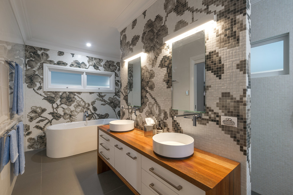 Photo of a contemporary master bathroom in Brisbane with flat-panel cabinets, white cabinets, black and white tile, a vessel sink, wood benchtops, a freestanding tub, an open shower, porcelain tile, white walls, porcelain floors, an open shower and brown benchtops.